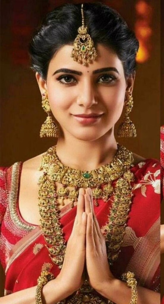 About Us 2 About Us This is an image of an Indian woman wearing a red saree and ethnic wear jewelry doing a Namaste.