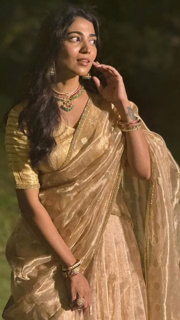This is an image of a woman wearing a gold and cream saree 