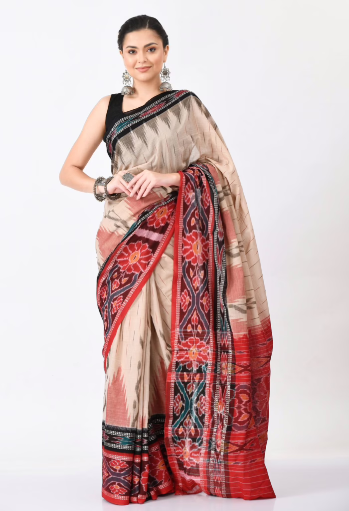 Woman wearing a handcrafted ivory handloom Ikat saree with a vibrant red woven border and traditional geometric motifs, paired with oxidised silver jewellery.