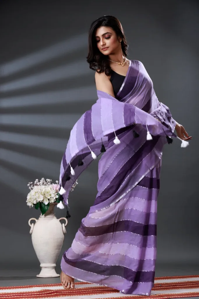 5 Super Simple Tips to Choose Your Saree Fall for the Perfect Drape 5 5 Super Simple Tips to Choose Your Saree Fall for the Perfect Drape Woman wearing a lavender and purple saree standing near a white flower vase