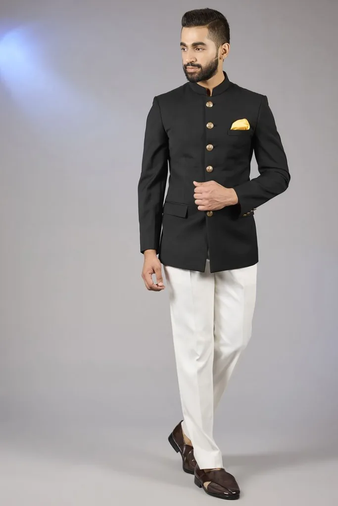 A man wearing a black Bandhgala suit with cream trousers.
