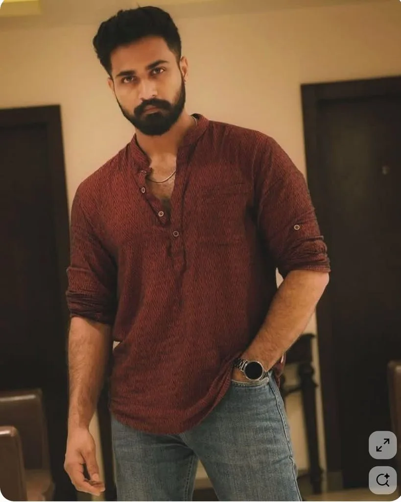 This is a picture of a young handsome man wearing a dark maroon kurta with blue jeans.